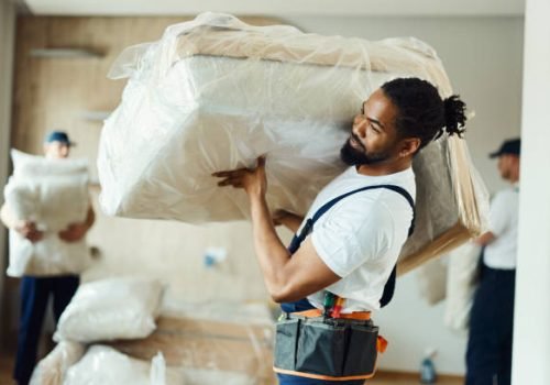 African American male mover carrying furniture in the apartment.